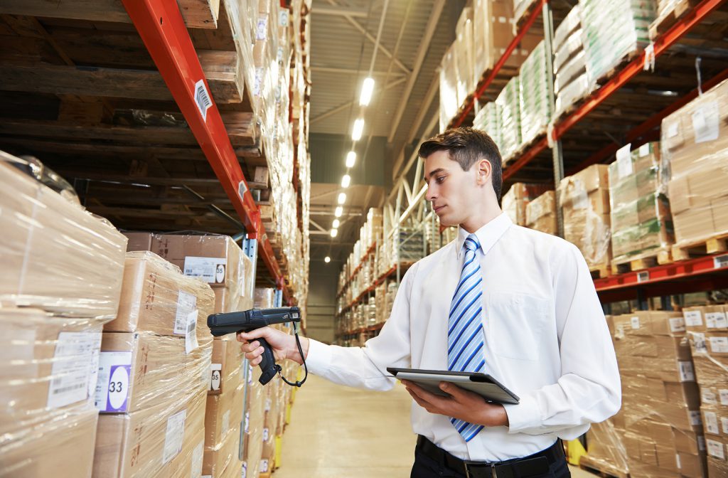A worker scanning pallets with a barcoding device. Our barcoding devices are crucial supply chain management tools.