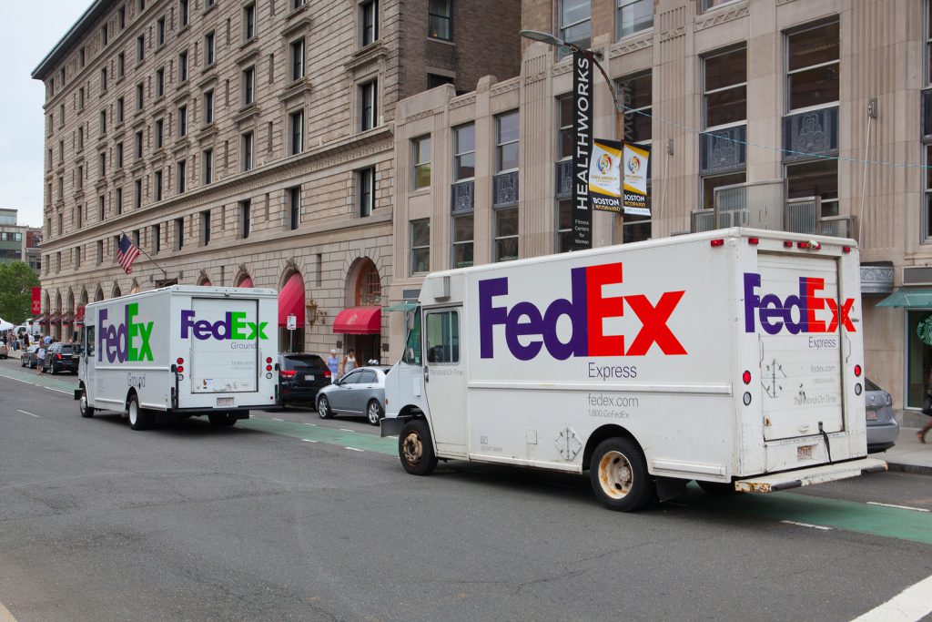 FedEx shipping trucks parked outside a building in the city. We help coordinate shipping for supply chain management.