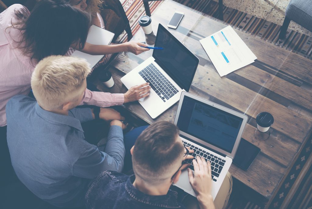 A group of people working together and discussing information on a laptop.