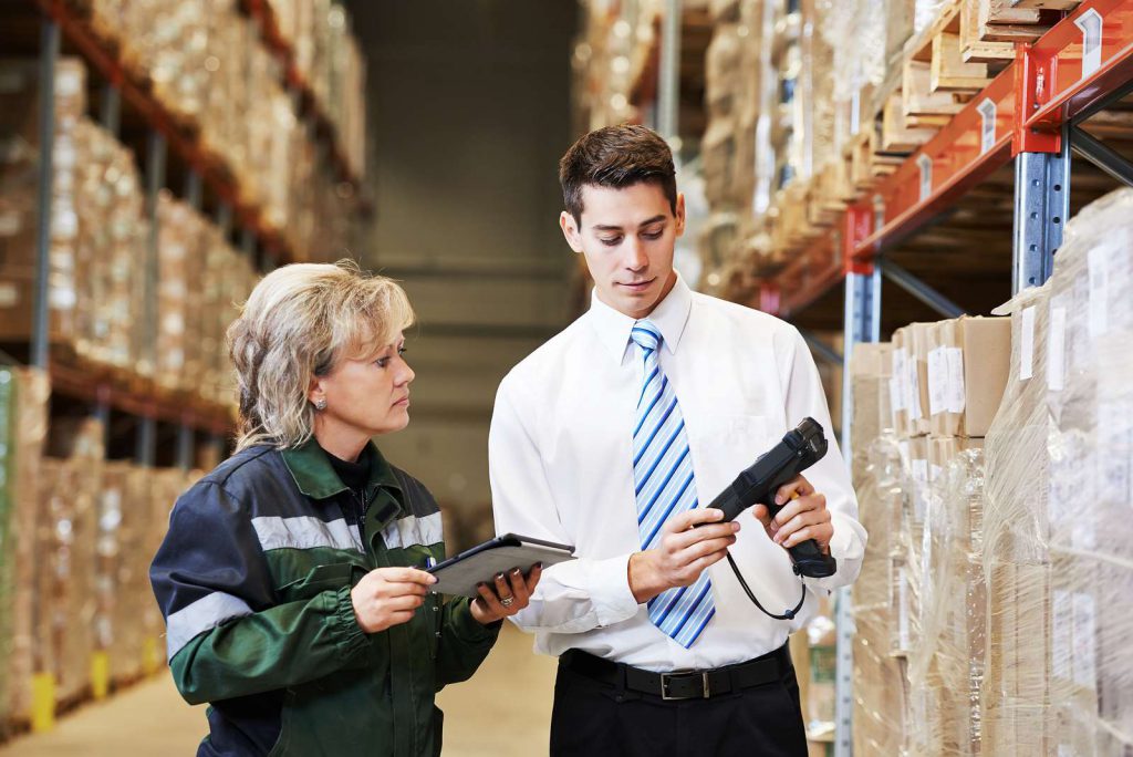 Two workers discussing information on the screen of a barcoding device. Our barcoding devices are valuable supply chain management tools.